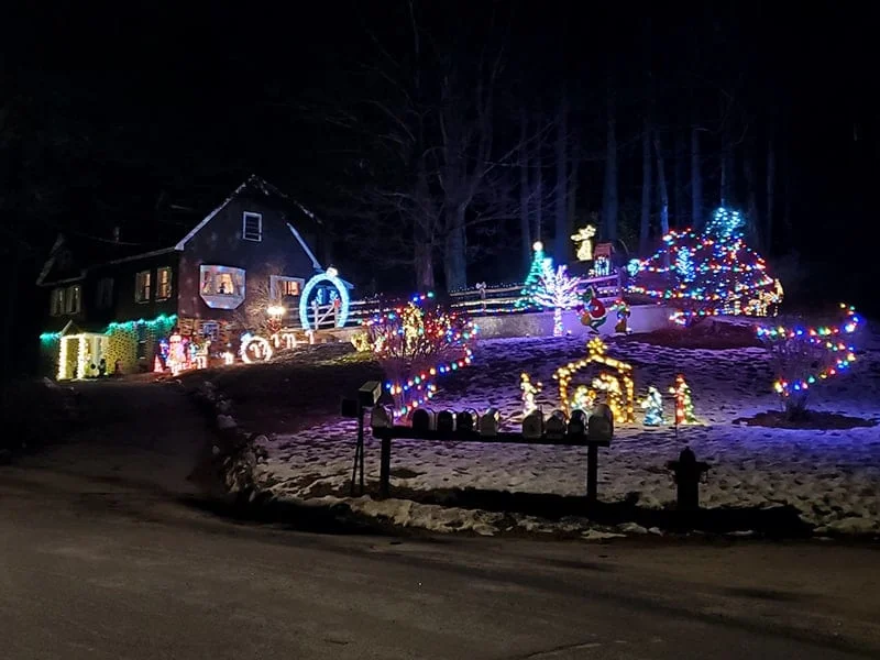 A house sits atop a hill surrounded by a wide display of christmas lights