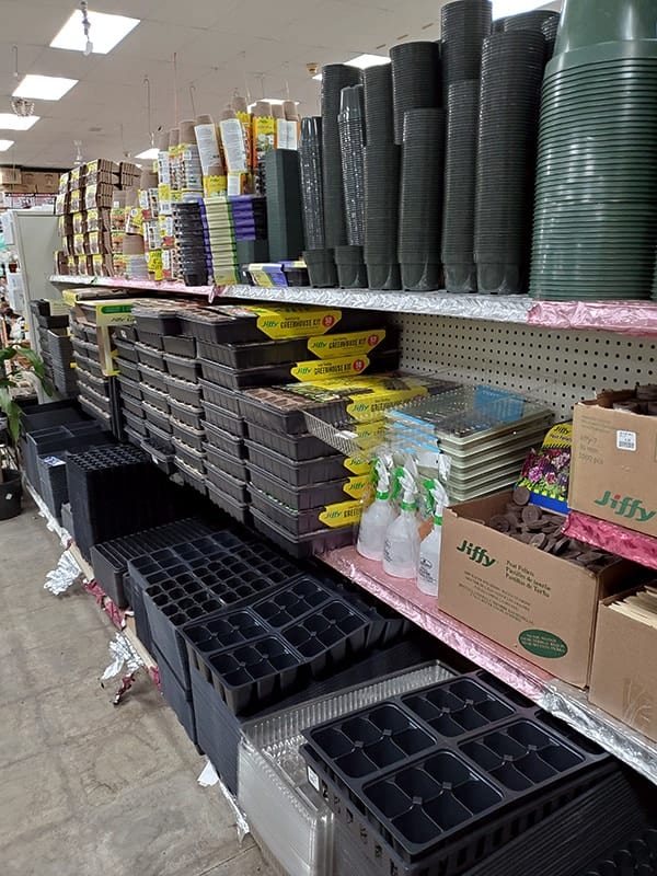 Aisle shelving lined with starter pots and trays for gardening