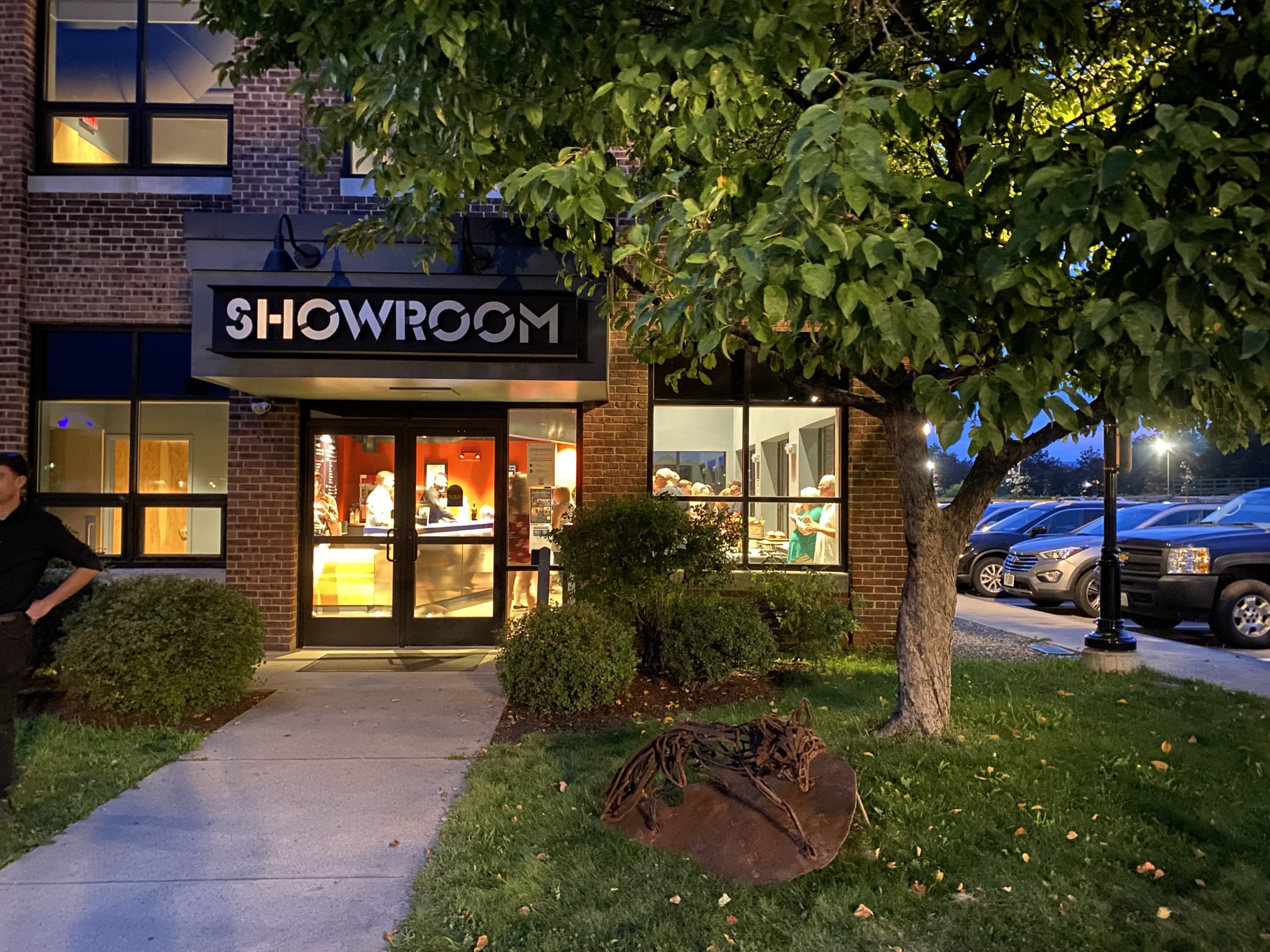 A grass lined path leads up to a brightly lit building with the name SHOWROOM above the doorway.