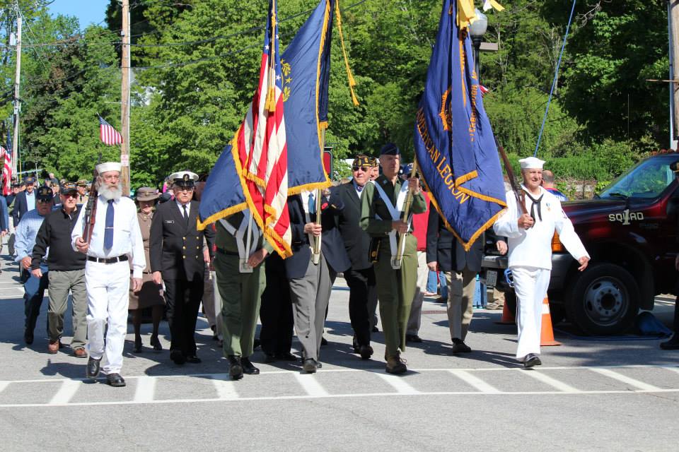 Several veterans wear their uniforms as they hold the flags and march at the front of the parade