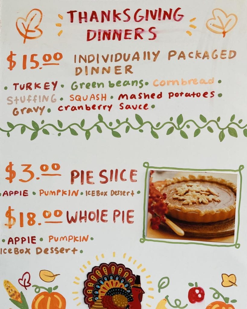 whiteboard with writing on the prices and offerings of individual thanksgiving meals