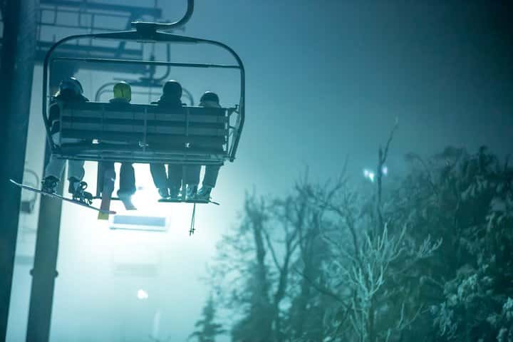 ski lift with skiers headed up the mountain in the evening