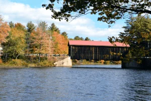 covered bridge over a lake with fall foliage surrounding it