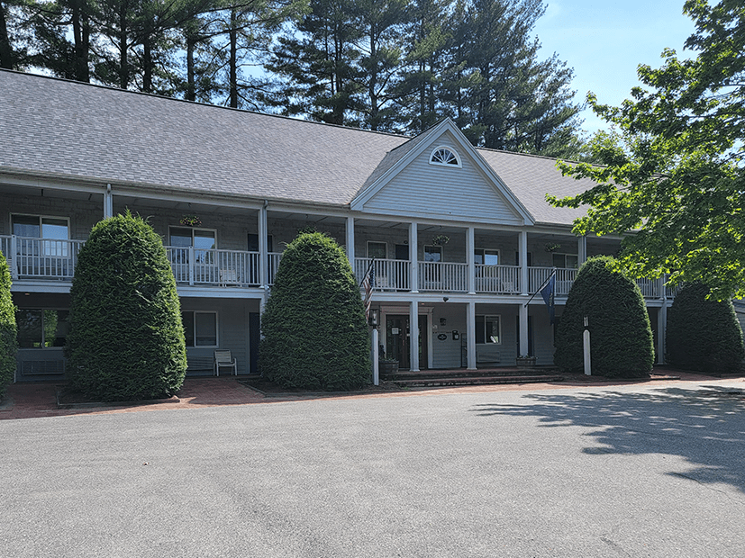 the Jack Daniels Inn's building surrounded by evergreen trees with the parking lot in front of the building