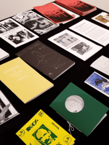 Multiple zines are lined up on a table for guests to flip through