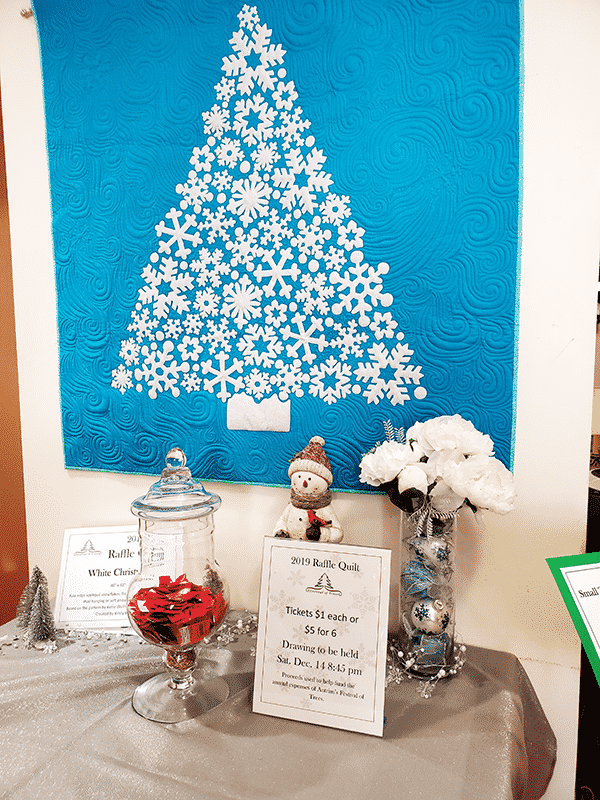A quilted christmas tree made out of white snowflakes on a blue background