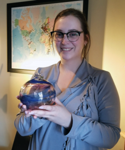 Woman holding a blown glass orb with swirls of blue and red