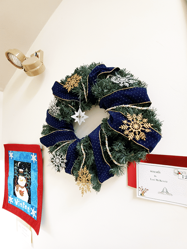 A wreath decorated with blue ribbon and gold snowflakes 